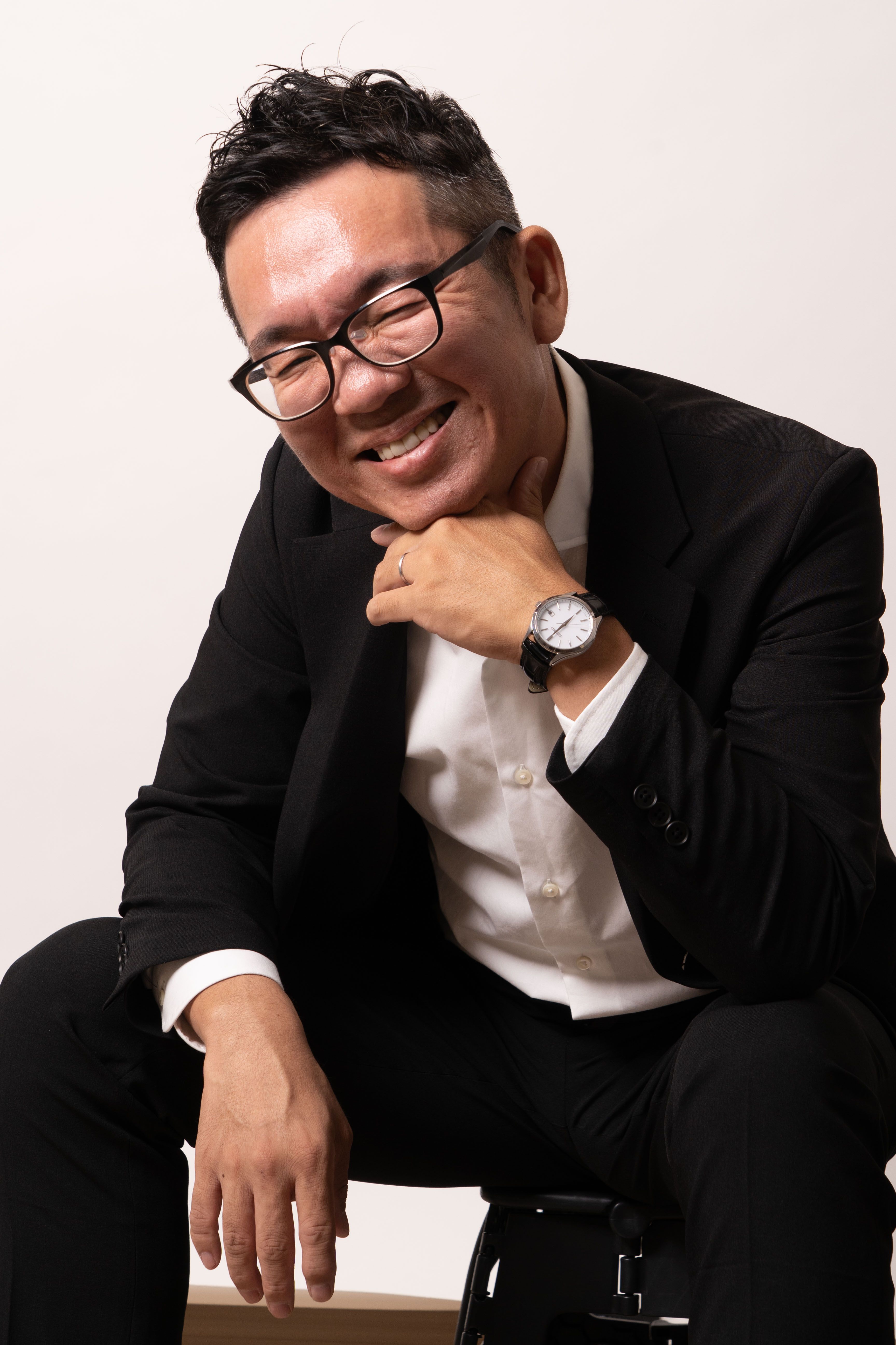 椅子に腰掛けて微笑む KENTARO WATANABE